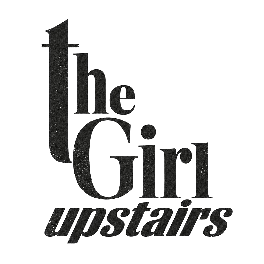 Black textured typography reading “the Girl Upstairs” on a light background.