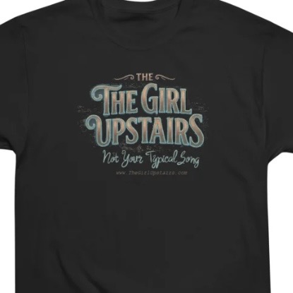 Black T-shirt featuring “The Girl Upstairs” logo with decorative teal lettering and small tagline beneath.