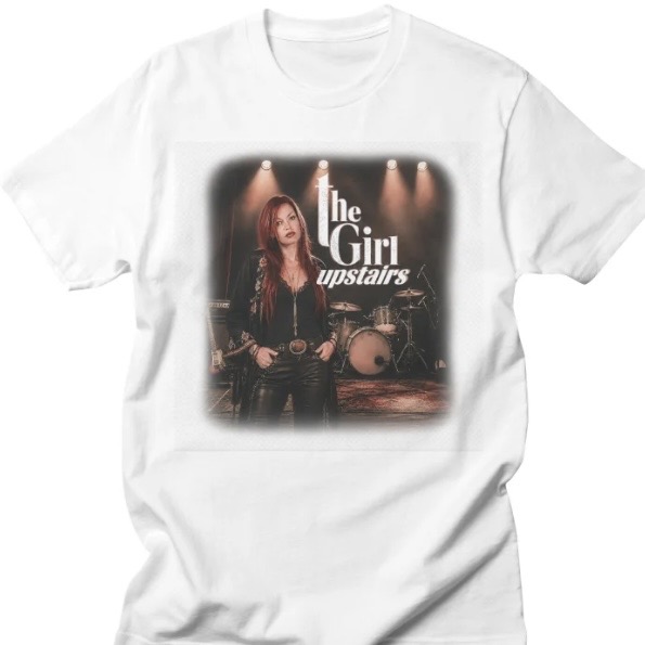 White T-shirt featuring a band poster graphic with a woman and drum set, “The Girl upstairs” text.