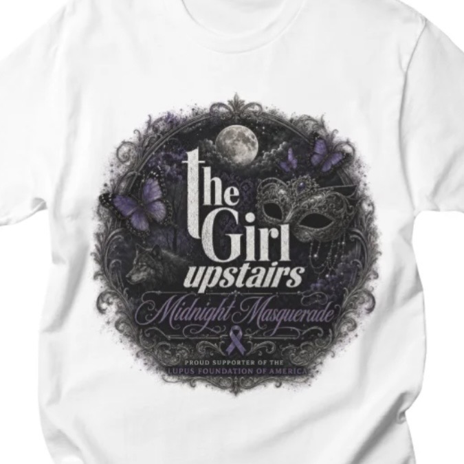White T-shirt featuring “The Girl Upstairs” logo with moon, masquerade mask, butterflies, and ornate purple design.